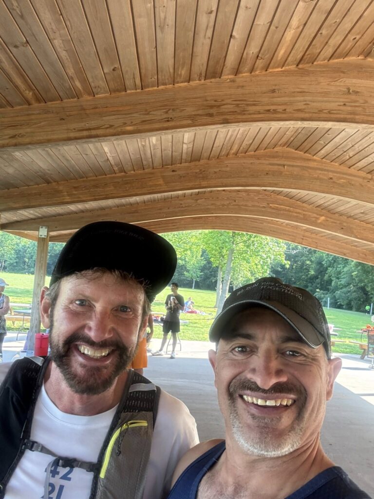 Victor and another coach smiling under wooden roof