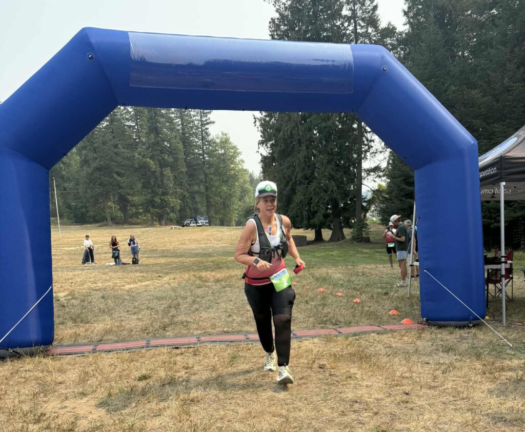 Runner crossing triathlon finish line under blue inflatable arch