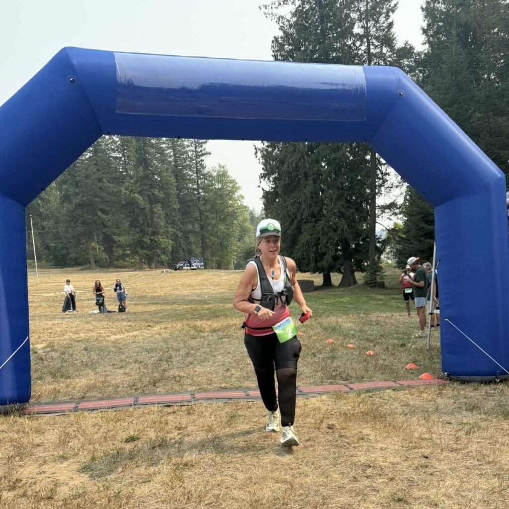 Runner crossing triathlon finish line under blue inflatable arch