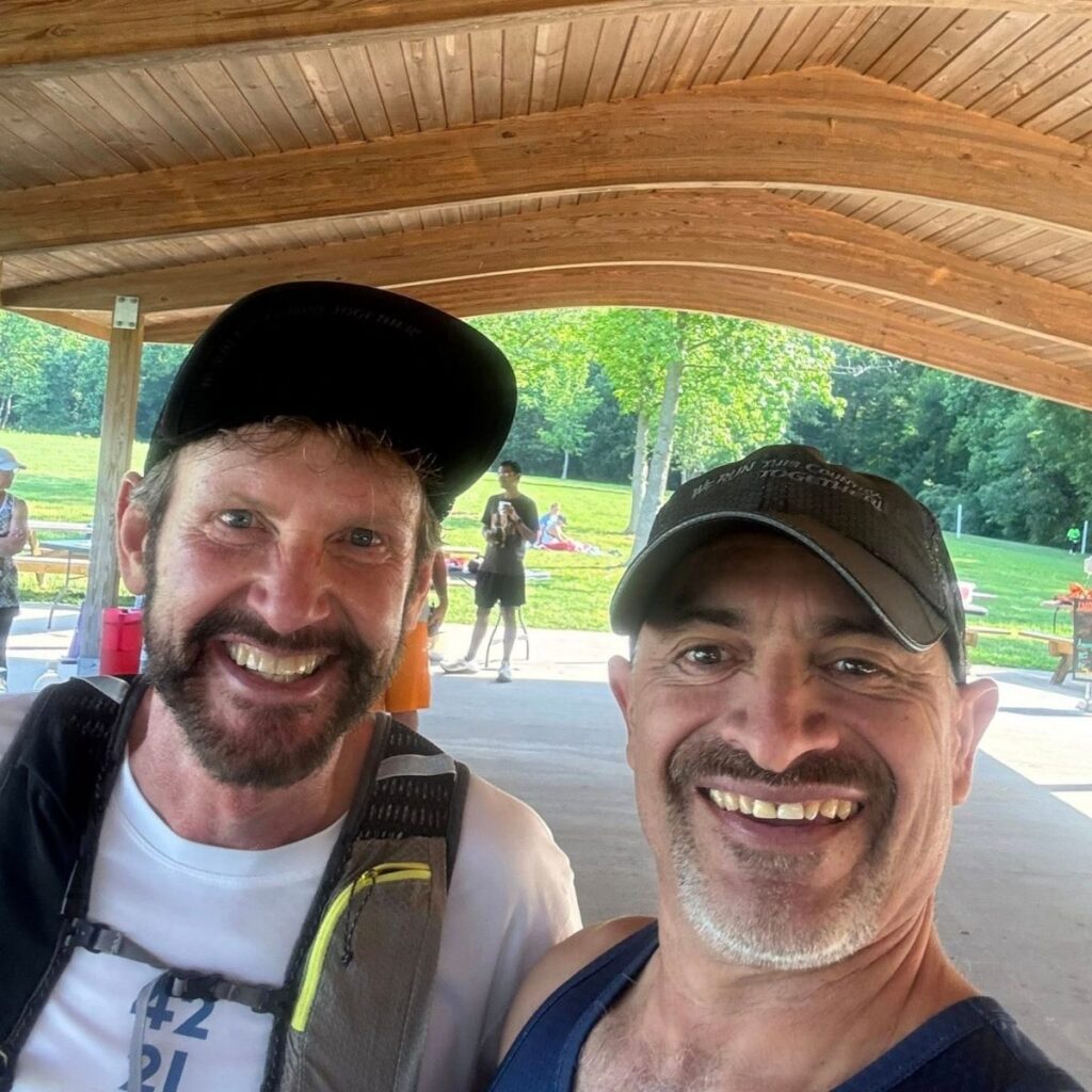 Life Coach Victor smiling with client under wooden roof